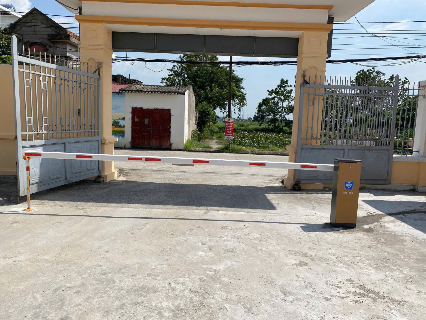 Thanh chắn barie tự động lắp đặt tại cổng cơ quan với trụ điều khiển màu vàng
